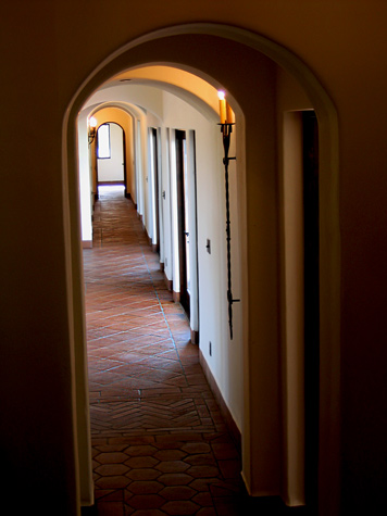 Long hallway of Spanish arches and clay tile floor in Spanish home in Santa Barbara, California